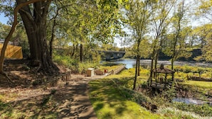 A pathway leading to a gazebo by a river, with a bridge in the background. - Beautiful, Bright Home Steps From Little Red River (Heber Springs)