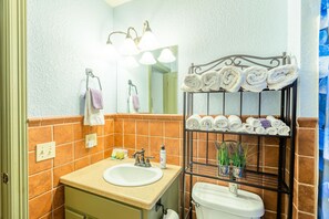 Une salle de bain équipée d’un lavabo, d’un miroir, d’un porte-serviettes et d’une étagère où sont rangées les serviettes.