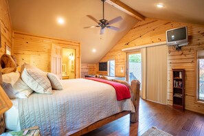 A bedroom with a bed, a ceiling fan, a television, and a bookshelf.