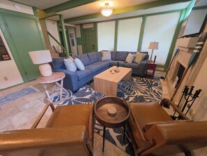 A living room with a sectional sofa, a coffee table, a small side table, and a fireplace.