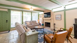 A living room with a fireplace, green walls, and a large window.