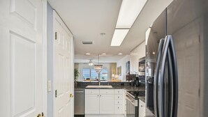 A modern kitchen with white cabinets, a black refrigerator, and a view to the outside.