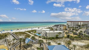 A beach resort with a pool, beach umbrellas, and a view of the ocean.