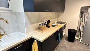 A modern kitchen with dark cabinets, a white sink, and a wooden countertop. - Appartement Neuf 83m² vue Mer, Pleins Coeur de St Florent (Saint-Florent)