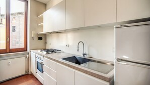 Una cucina moderna con mobili bianchi, un lavello in acciaio inossidabile, un piano cottura a gas e un forno integrato.