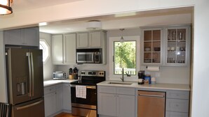 A modern kitchen with stainless steel appliances, grey cabinets, and a wooden floor.