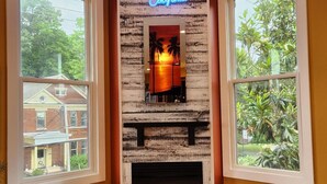 Una habitación con chimenea, un letrero de neón que dice "Hotel California" y ventanas amplias con vistas al exterior.