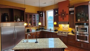 Una cocina moderna con encimeras de granito, electrodomésticos de acero inoxidable y armarios de madera.