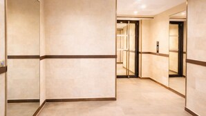 A modern hotel corridor with mirrored walls, a central elevator, and a tiled floor. - Luxury just 10 minutes from central Paris. Free Parking (Vitry-sur-Seine)