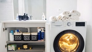 A laundry area with a front-loading washing machine, a sink with toiletries, and neatly folded towels on top. - Luxury just 10 minutes from central Paris. Free Parking (Vitry-sur-Seine)