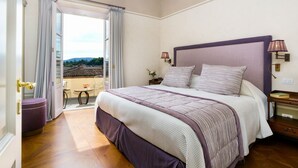 Un dormitorio con una cama grande, una mesita de noche, una lámpara y vistas al exterior.