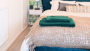 Camera da letto con un letto, un comodino, una lampada e una parete decorata con un motivo a foglia.