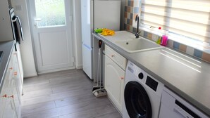 Una cucina funzionale con lavatrice, frigorifero e lavello.