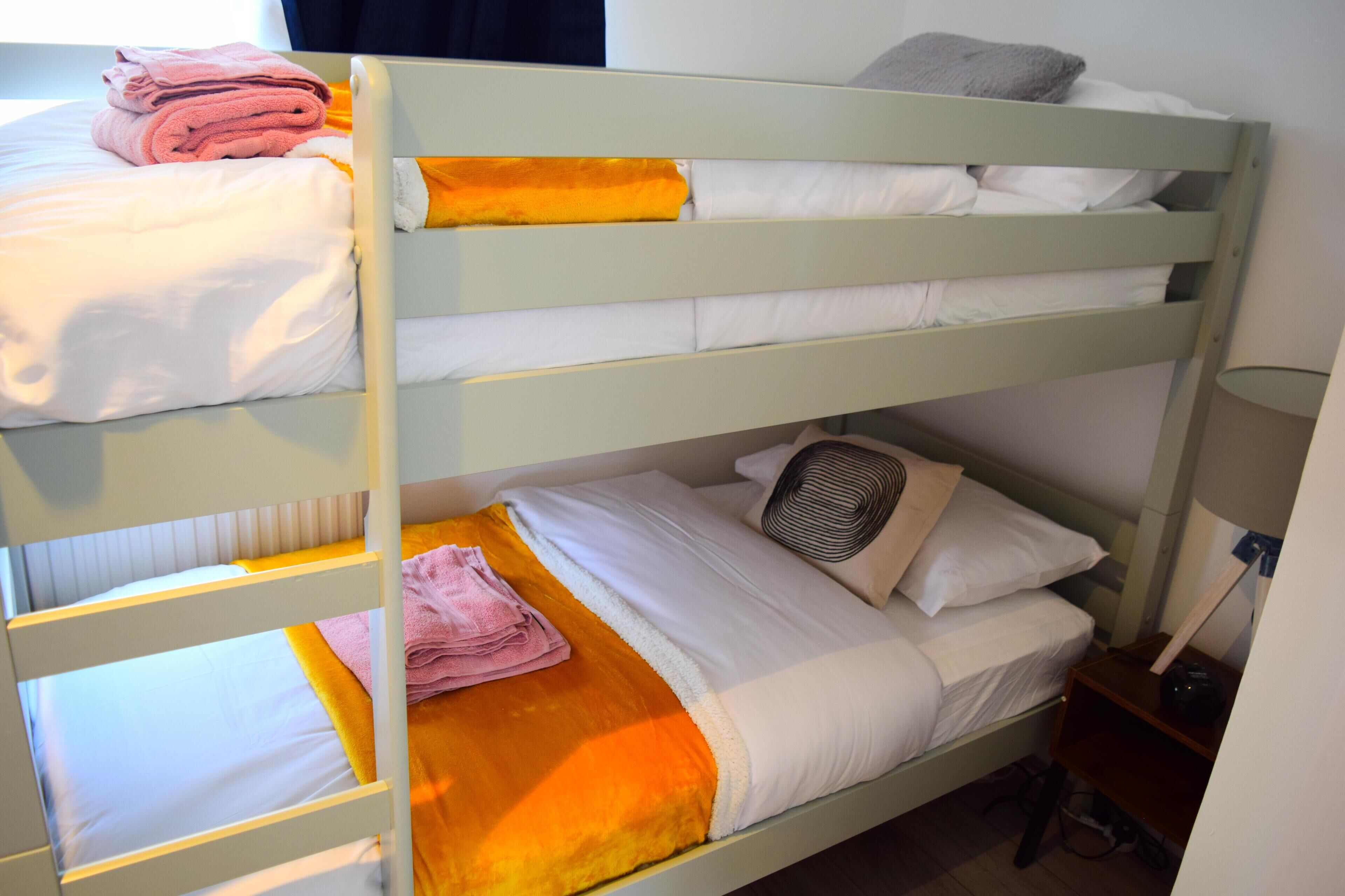 A bunk bed with two levels, each with a pillow and a folded towel.