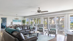 A spacious living room with a large sofa, armchairs, and a dining area. - Windy Dunes, Almost Oceanfront House in Emerald Isle, NC! (Emerald Isle)