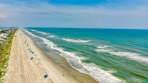 A beach with a long stretch of sand, waves, and a clear sky. - Windy Dunes, Almost Oceanfront House in Emerald Isle, NC! (Emerald Isle)