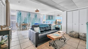 A modern living room with a leather sofa, a wooden coffee table, and a dining area with a table and chairs. - Sunset views over the Gulf.  Beachside BEST.  The perfect getaway for two!   (Panama City Beach)