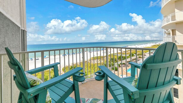 A balcony with two green Adirondack chairs, a small table, and a view of the beach and ocean. - Sunset views over the Gulf.  Beachside BEST.  The perfect getaway for two!   (Panama City Beach)