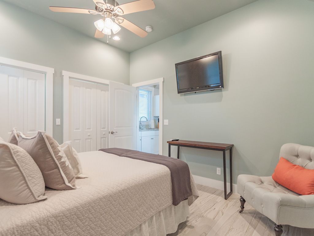 A bedroom with a bed, a ceiling fan, a TV, and a chair.
