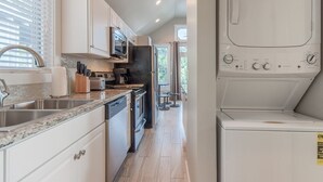 Une cuisine moderne avec des armoires blanches, des appareils en acier inoxydable et un lave-linge et un sèche-linge intégrés.