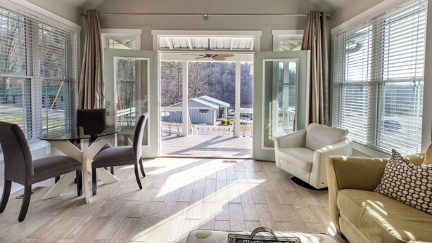 A spacious living room with a glass dining table, comfortable seating, and a view of a backyard.