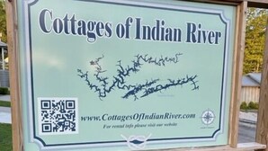 A sign for Cottages of Indian River with a QR code and a website URL.
