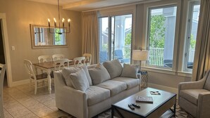 Una sala de estar con un sofá color beige, una mesita de centro y un comedor con mesa y sillas.