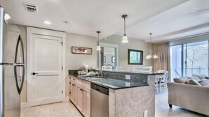 Una cocina moderna con una isla central, electrodomésticos integrados y un comedor con sofá y sillas.