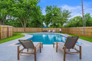 A backyard with a swimming pool, wooden deck, and lounge chairs. - Poolside Paradise: Arcade & Firepit Fun (Deer Park)