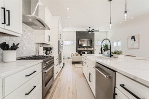 A modern kitchen with white cabinetry, stainless steel appliances, and a central island. - Eden Ranch Home (Centennial)