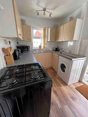 Kitchen features a gas stove, microwave, and washing machine, with ample natural light and ample storage.