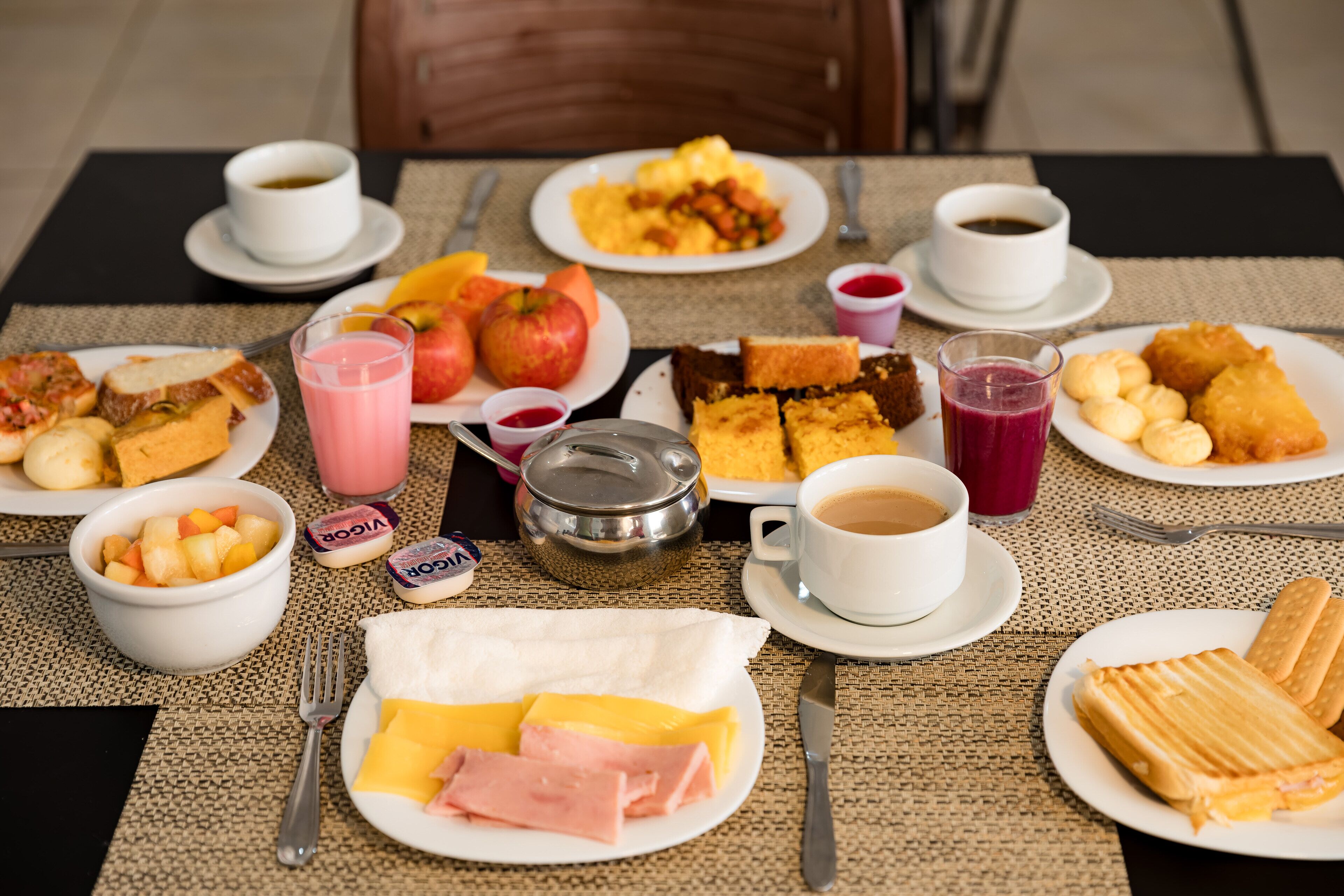 A breakfast table with various dishes, including fruits, bread, and beverages.