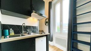 Una cocina compacta con encimera negra, un lavabo blanco y un refrigerador pequeño blanco.