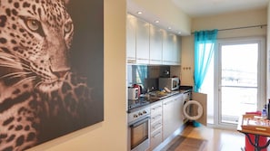 Une cuisine moderne équipée d’un lave-linge, d’un four à micro-ondes et d’une grande fenêtre avec des rideaux.