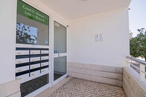 Une entrée d’immeuble avec une porte en verre, un portail en métal et un sol carrelé.