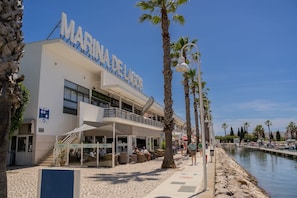 Hotel aan het water met een opvallend bord, terras en een zwembadgedeelte.