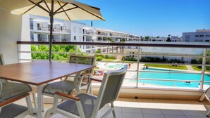 A balcony with a table and chairs, overlooking a swimming pool and a residential area. - Exquisite Apartment on the Lagos Marina - Marina Retreat (Lagos)