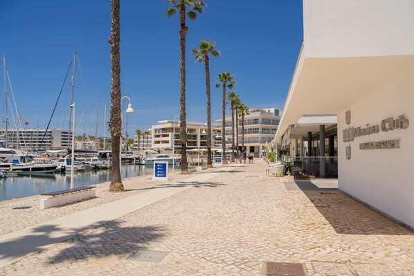 A marina with boats, a white building with a sign, and palm trees.