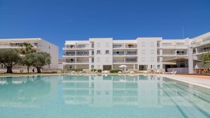 A hotel with a swimming pool, multiple balconies, and a clear blue sky. - Exquisite Apartment on the Lagos Marina - Marina Retreat (Lagos)