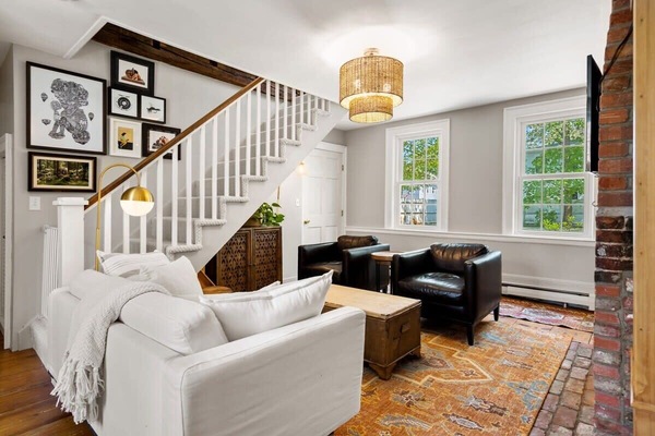 Living room with smart TV, couch, accent chairs and dedicated "work-from-home" desk. The fireplace is inoperable.
