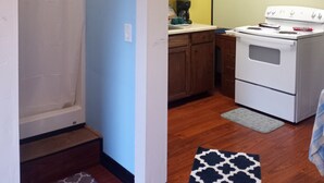 Una cocina compacta con estufa, armarios y un cuadro en la pared.
