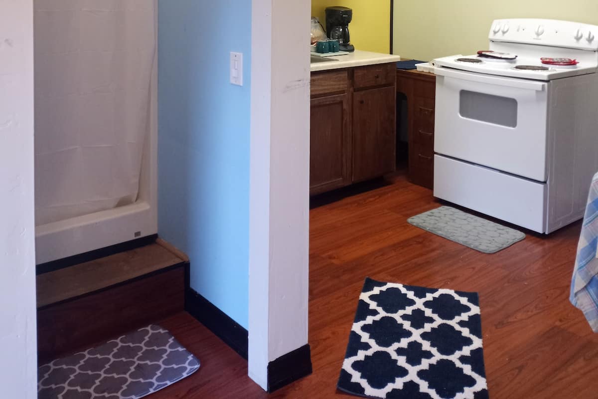 A compact kitchen with a stove, cabinets, and a painting on the wall.