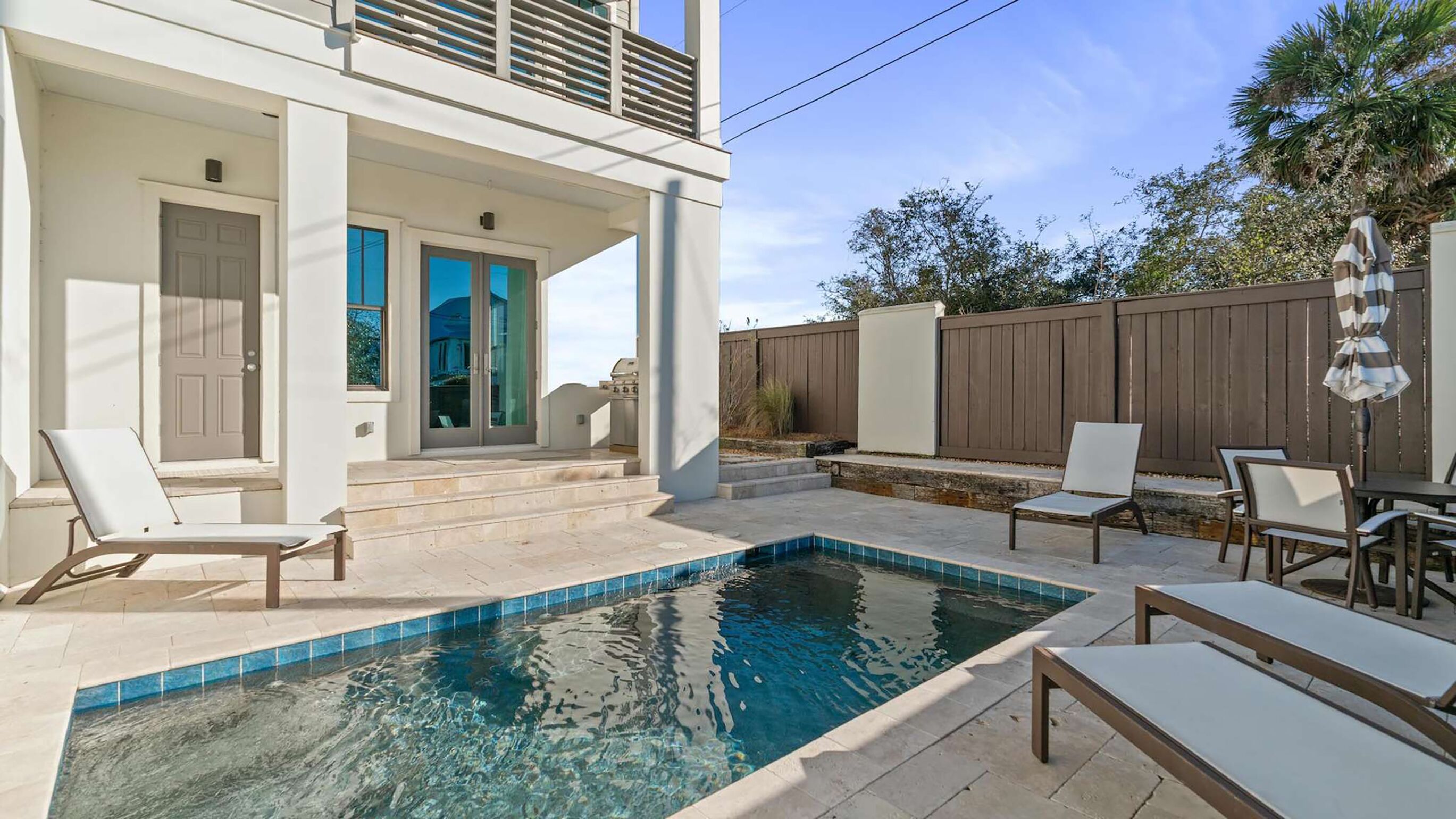 Una casa moderna con piscina, mobiliario exterior y valla de madera.