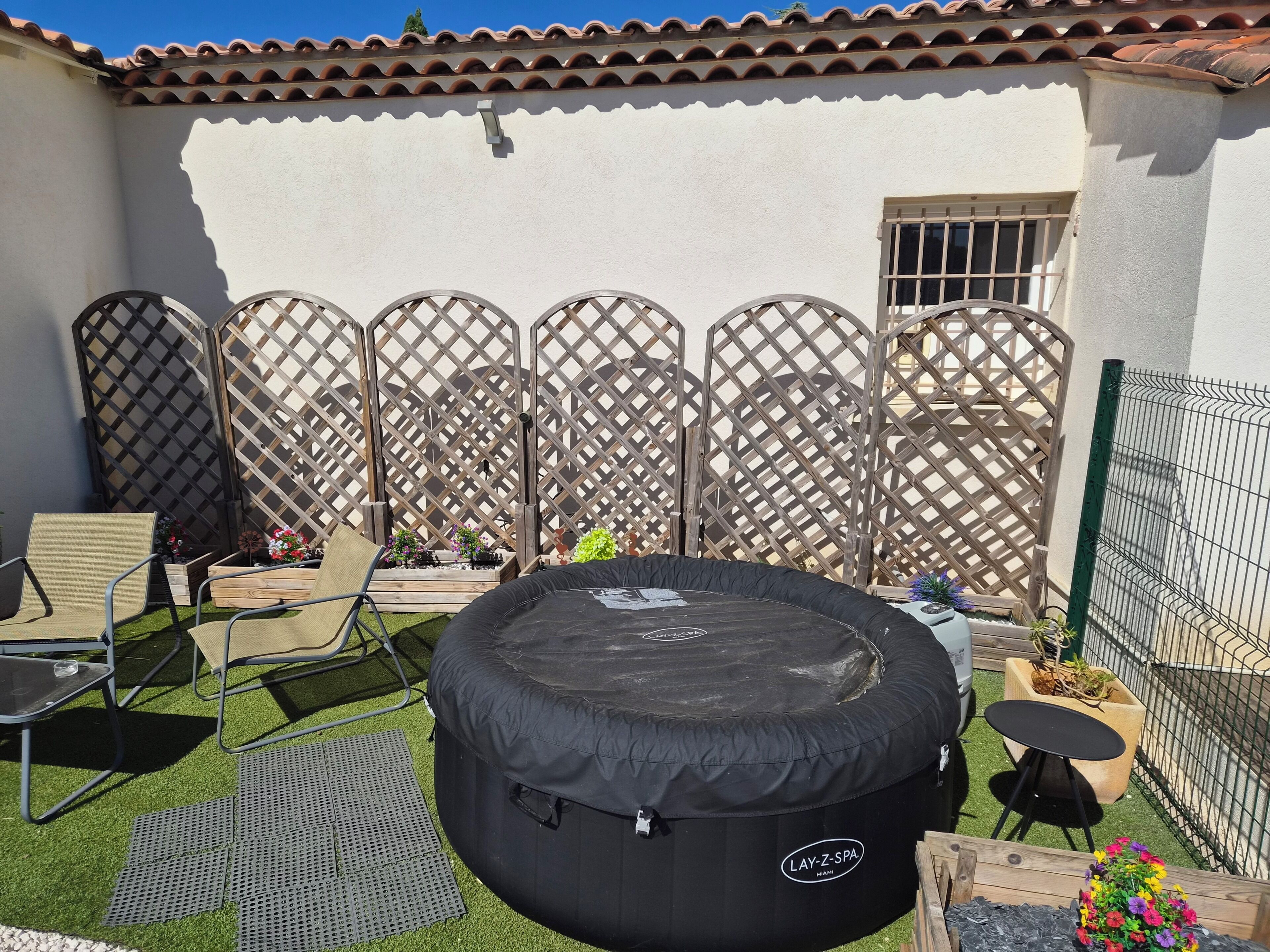 A patio with a black inflatable pool, outdoor furniture, and a decorative fence.
