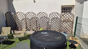 A patio with a black inflatable pool, outdoor furniture, and a decorative fence.