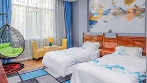 Une chambre d’hôtel avec deux lits, un fauteuil suspendu et une grande fenêtre avec des rideaux.