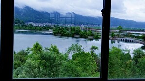 Une vue sur un lac avec un pont, entouré de verdure et de montagnes.