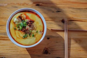 A bowl of soup with chopsticks and a wooden table. - Qianshuiwan Hotel (Tengchong)