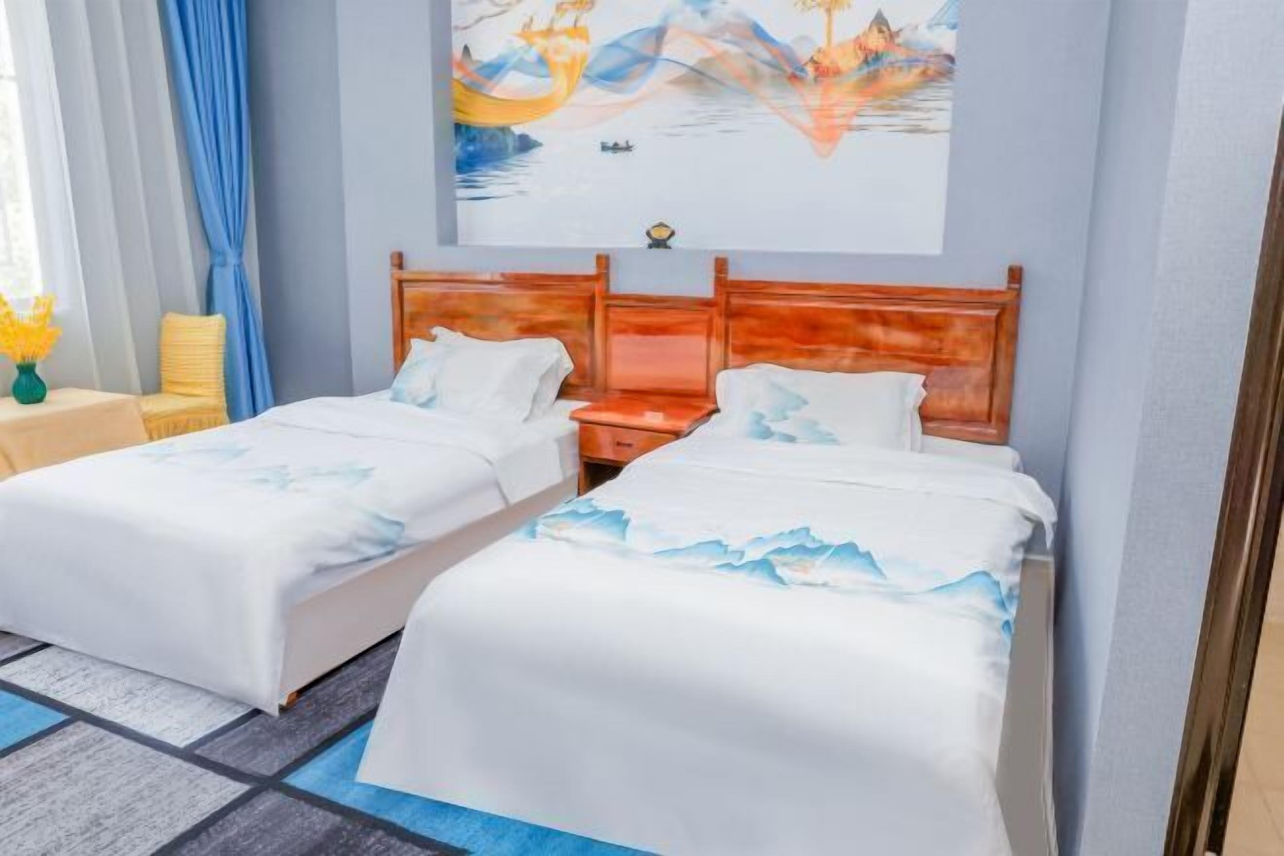 A hotel room with two beds, a wooden headboard, a painting on the wall, and a small table with a vase of flowers.