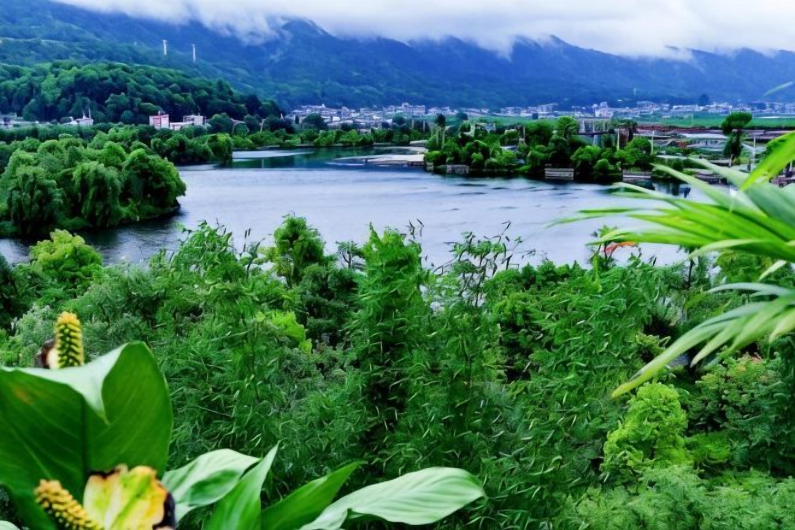 A river with lush greenery and a town in the background.